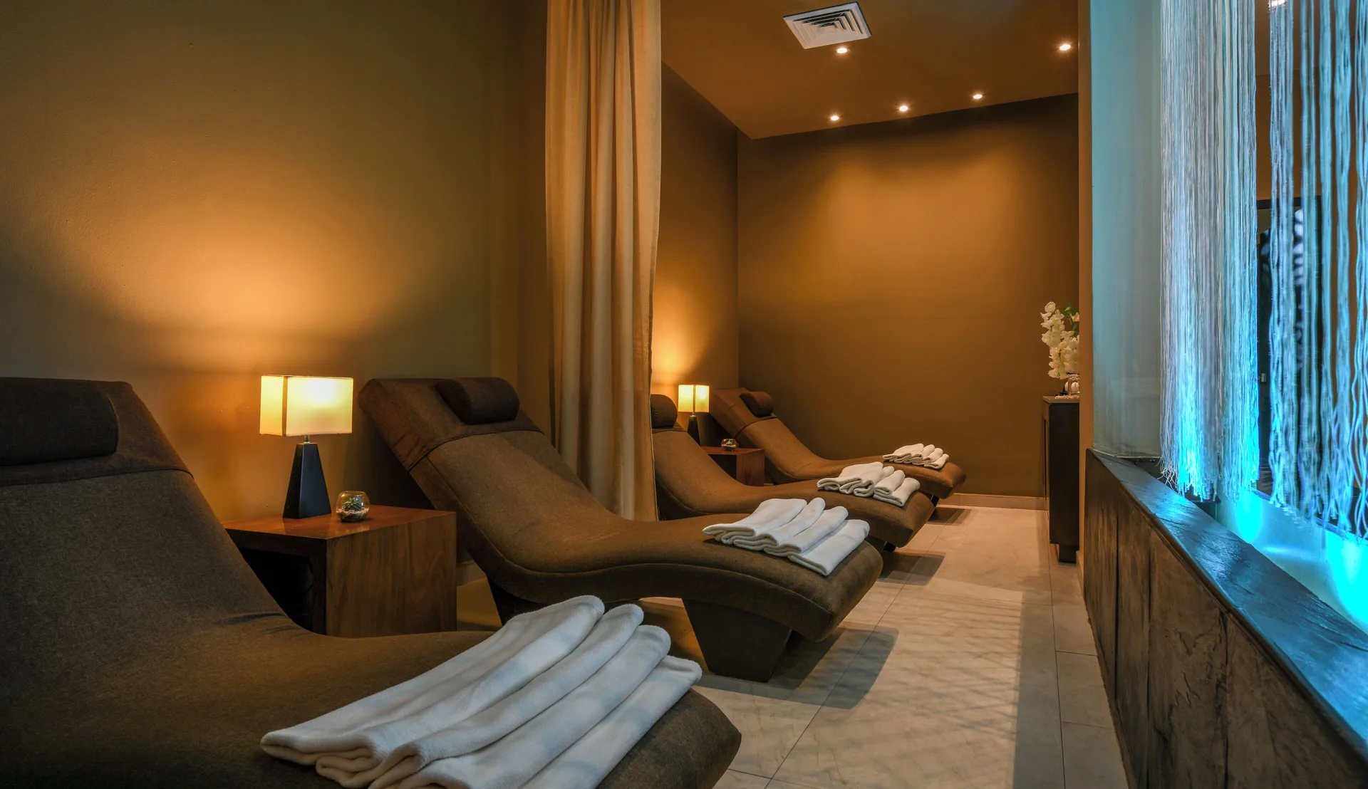 Spa relaxation room with loungers and folded towels at Generations Riviera Maya.