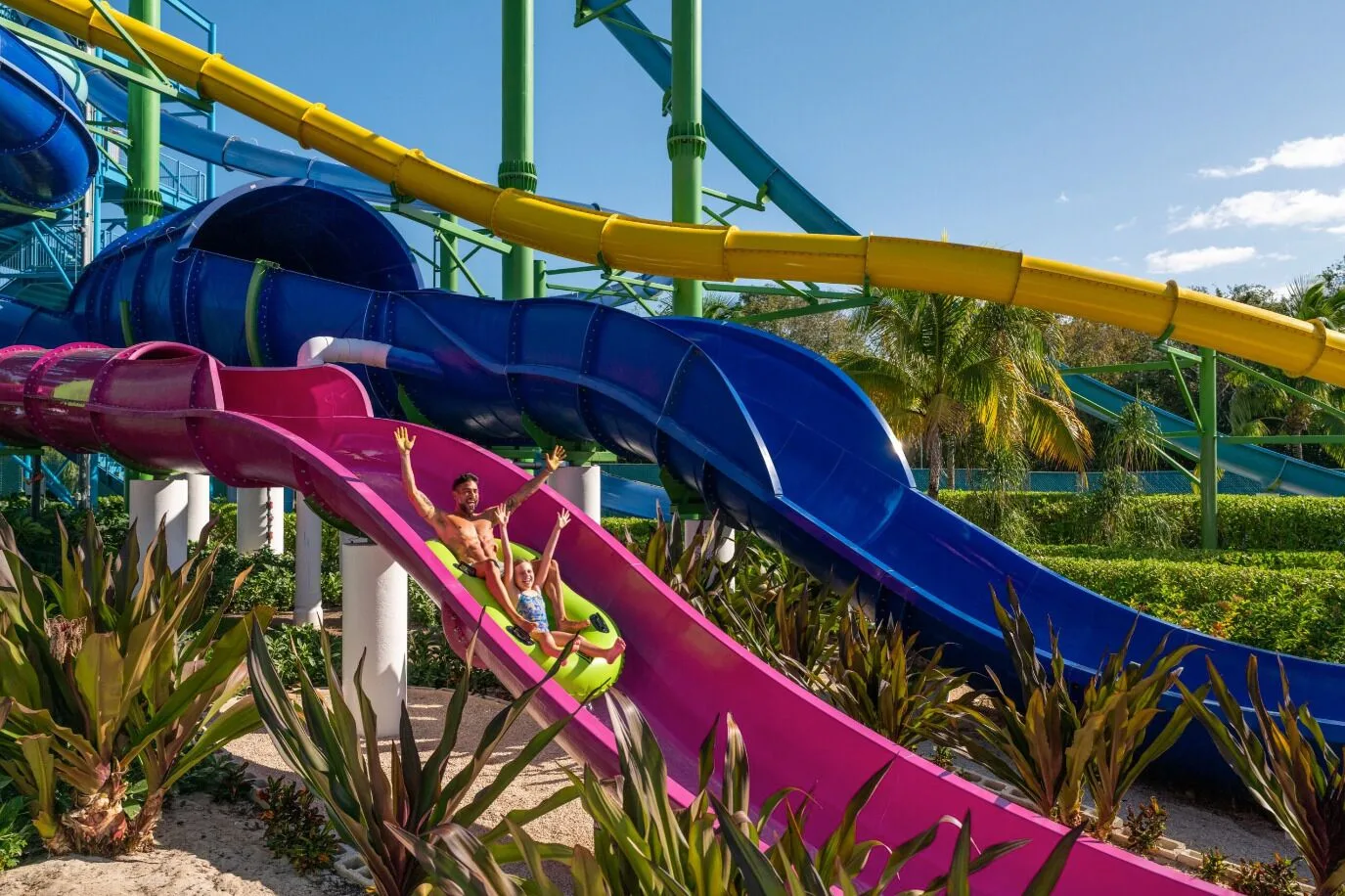 Family riding a bright pink waterslide at Generations Riviera Maya.