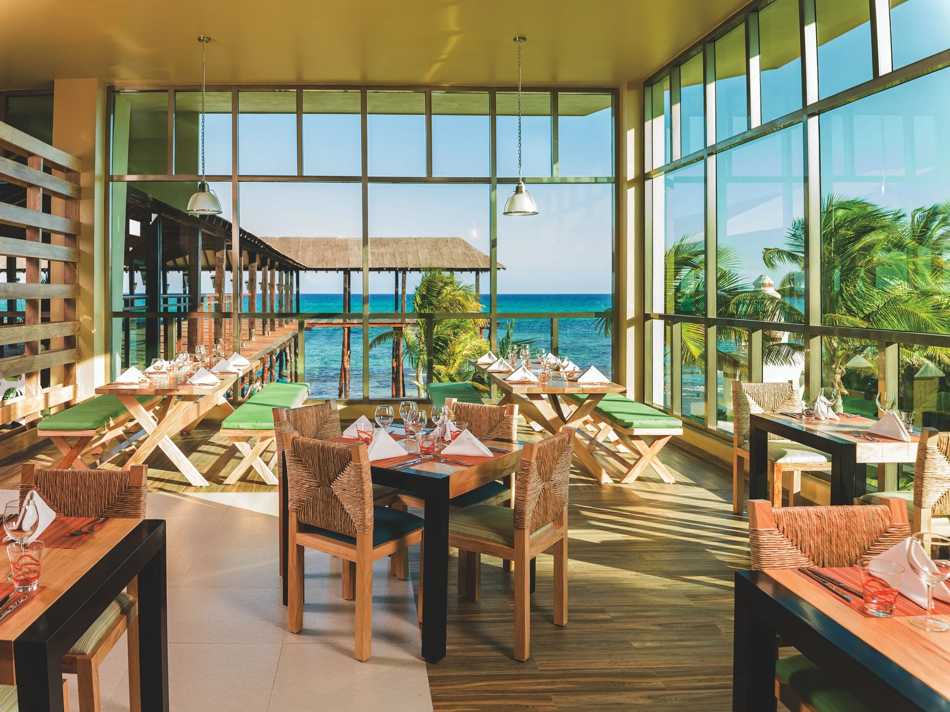 An ocean-view dining room with set tables at Generations Riviera Maya.
