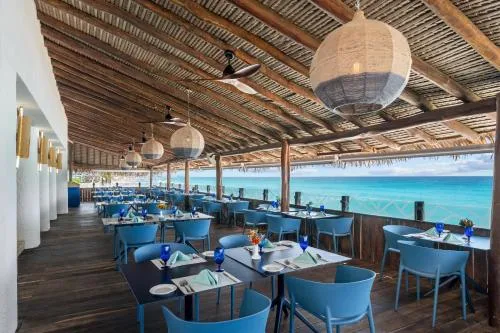 Covered oceanfront dining terrace with blue chairs at GR Solaris Caribe.