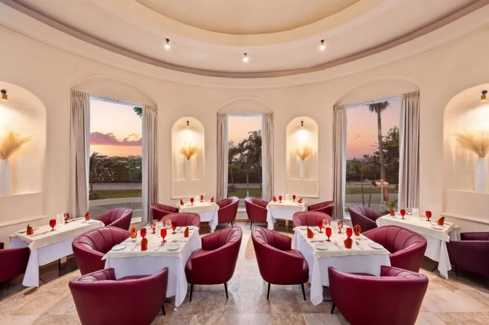 Elegant dining room with red chairs and sunset windows at GR Solaris Caribe.