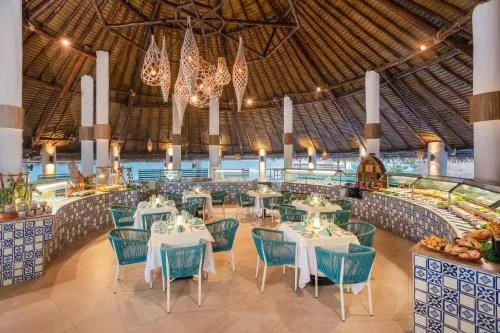 Thatched-roof buffet dining room with set tables at GR Solaris Caribe.