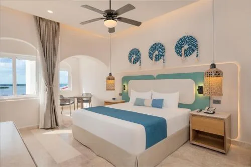 Deluxe Lagoon View room with king bed, bedside tables, pendant lights, and window nook at GR Solaris Caribe.