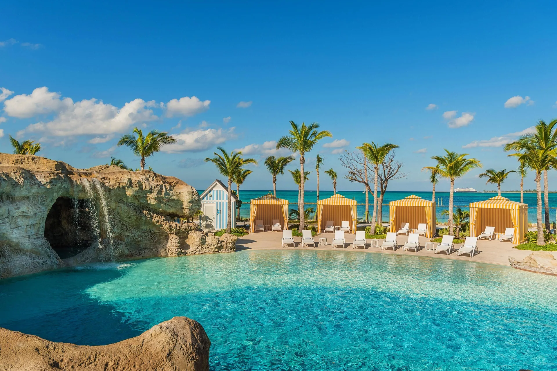Beachfront pool with rock waterfall and striped cabanas at Grand Hyatt Baha Mar.