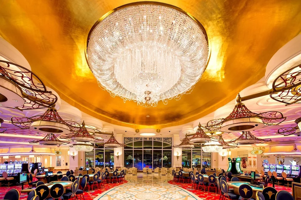 Casino floor with large chandelier, gold ceiling, and gaming tables at Grand Hyatt Baha Mar.