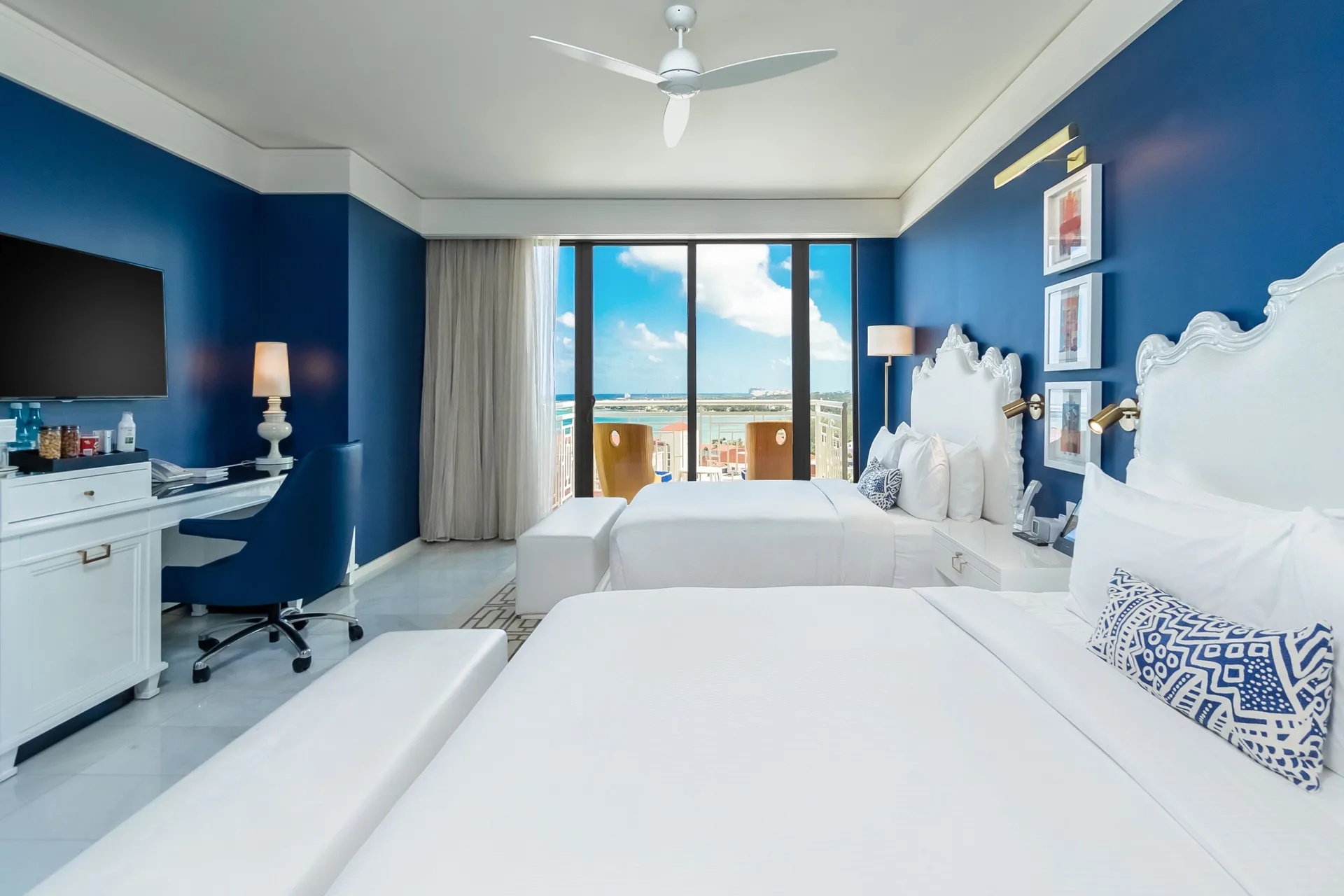 Guest room with two beds, blue walls, balcony, and ocean view at Grand Hyatt Baha Mar.
