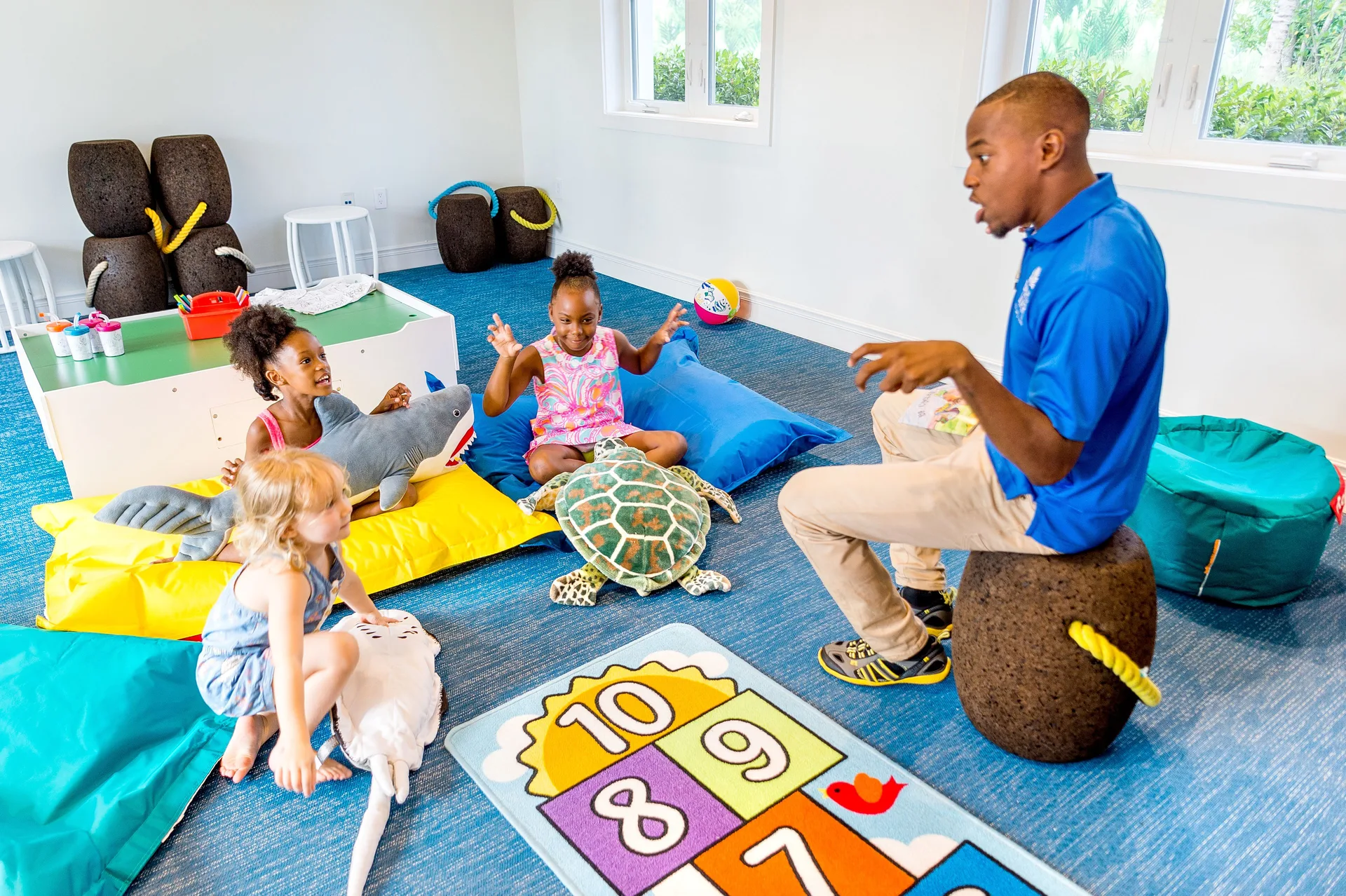 Children listening to a staff member in a playroom at Grand Hyatt Baha Mar.