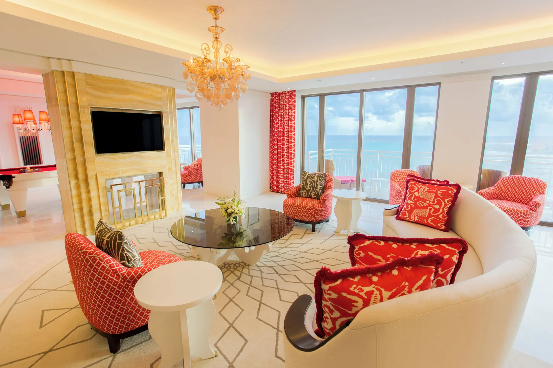 Oceanfront suite living room with curved sofa and red chairs at Grand Hyatt Baha Mar.