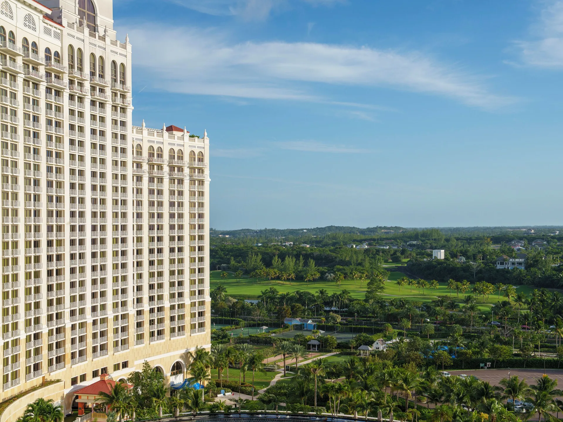 Tall resort tower overlooking green grounds and distant fairways at Grand Hyatt Baha Mar.