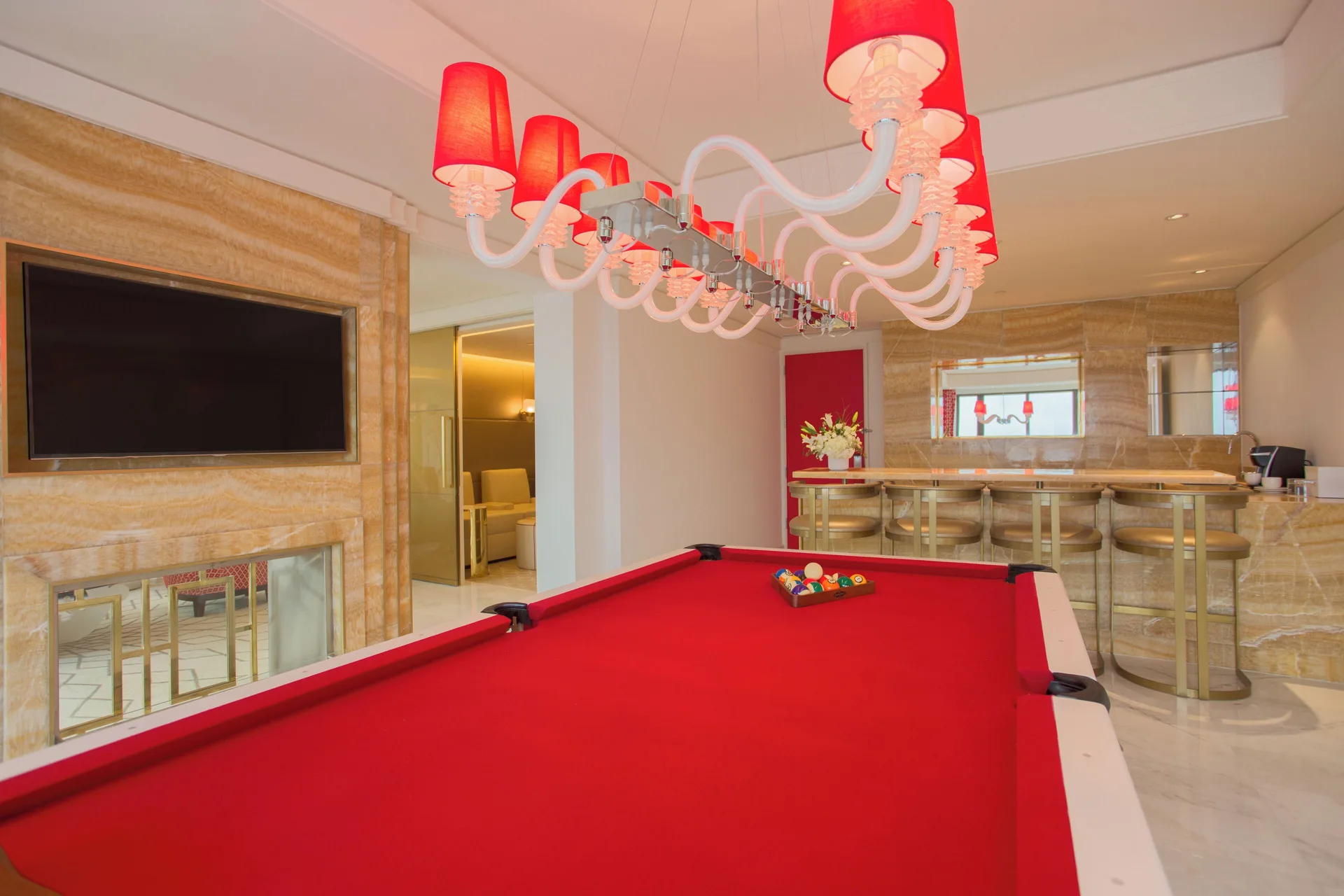 Suite game room with a red pool table, chandelier and bar counter at Grand Hyatt Baha Mar.