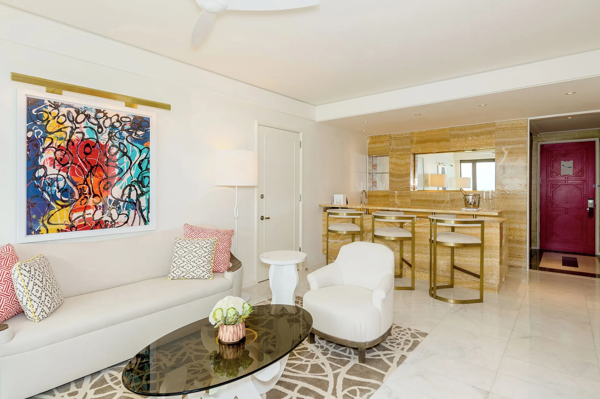 Bright suite sitting area with sofa, bar seating and colorful art at Grand Hyatt Baha Mar.