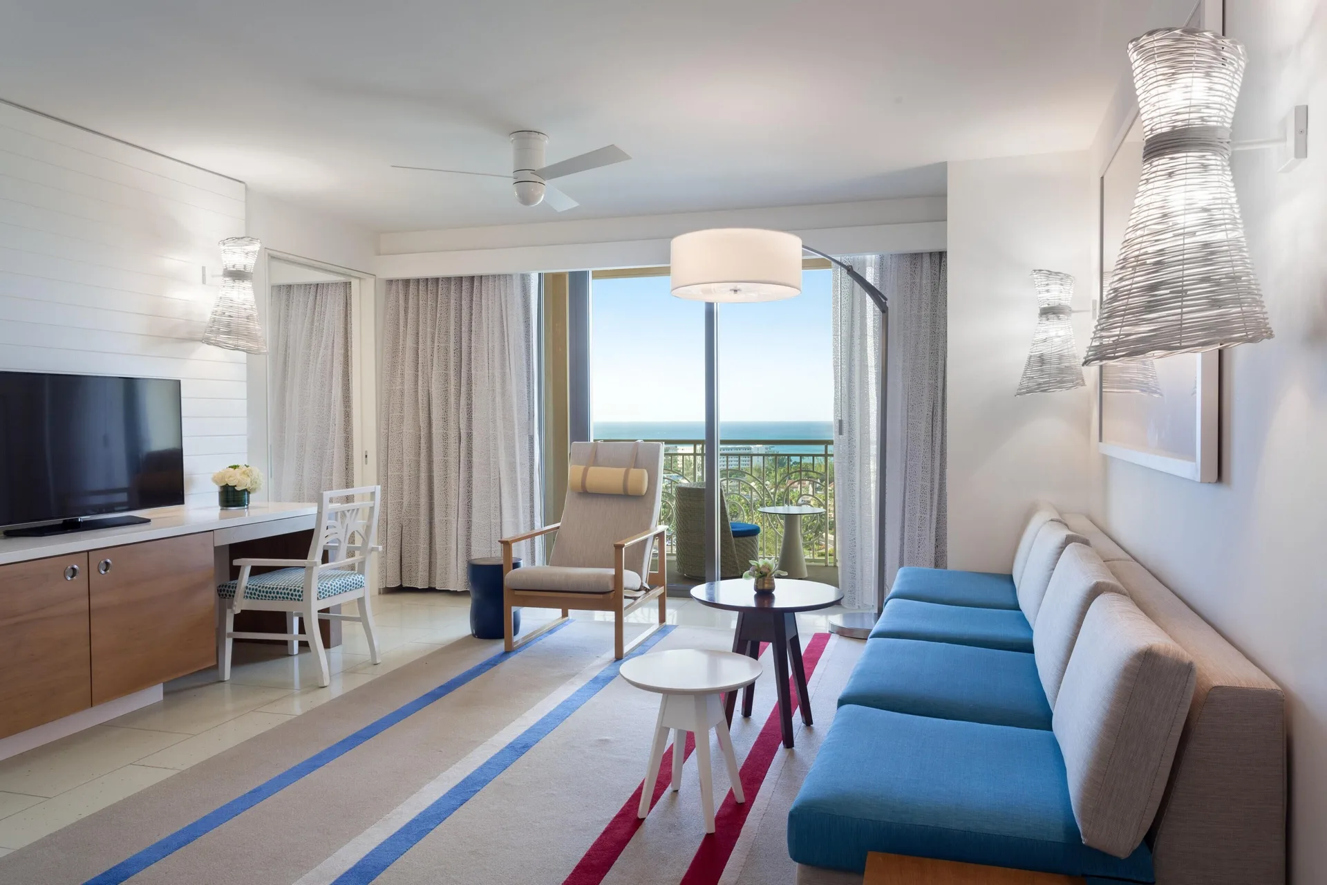 Suite sitting room with blue sofa and ocean-view balcony at Grand Hyatt Baha Mar.