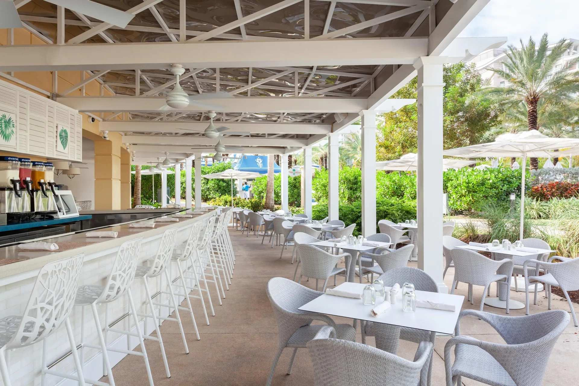 Covered outdoor café seating with white bar stools at Grand Hyatt Baha Mar.