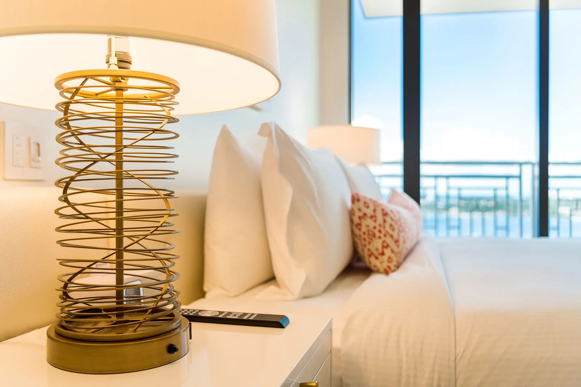Grand Suite bedside lamp and king bed with balcony beyond at Grand Hyatt Baha Mar.