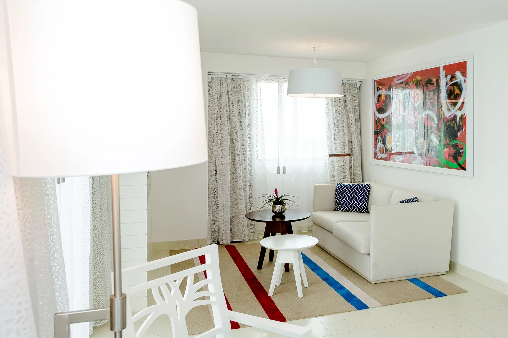 Grand Suite sitting area with white sofa, tables, lamp, and colorful art at Grand Hyatt Baha Mar.
