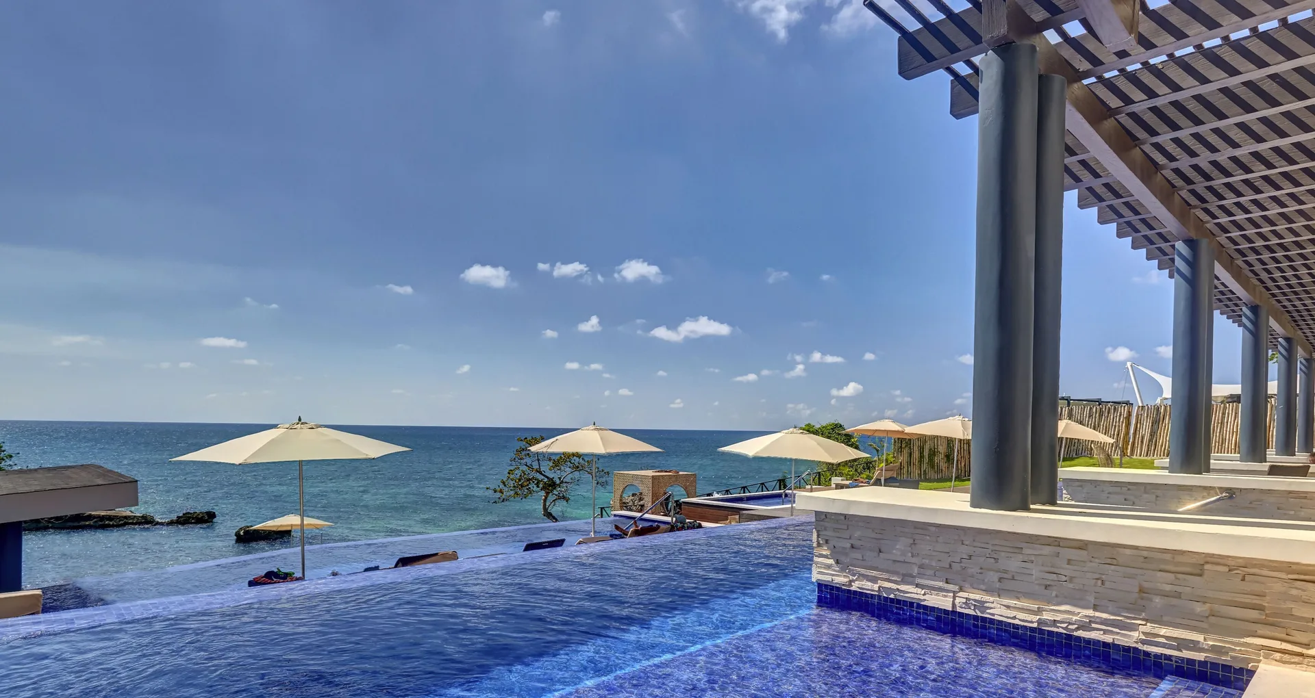 Infinity pool with umbrellas beside the Caribbean at Grand Lido Negril Au-Naturel.