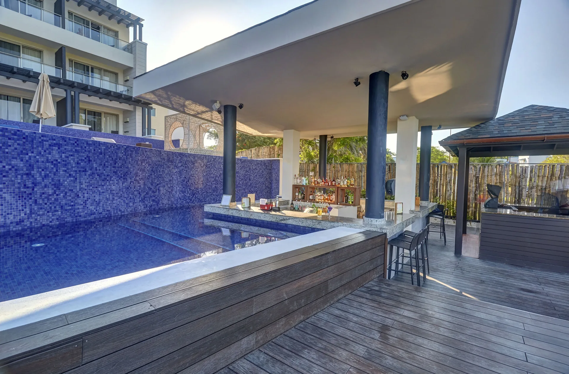 Open-air pool bar beside blue tile and wood decking at Grand Lido Negril Au-Naturel.