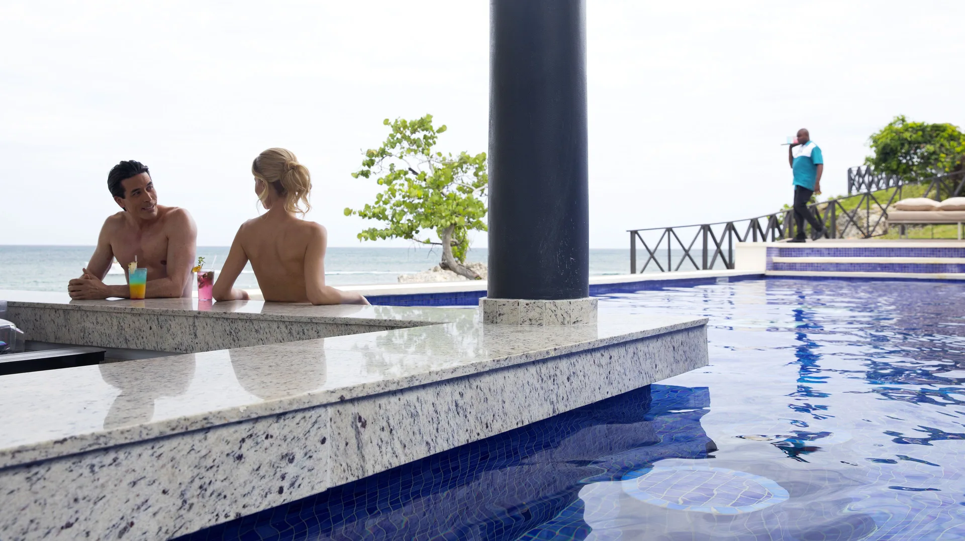 Swim-up pool bar with guests and ocean view at Grand Lido Negril Au-Naturel.