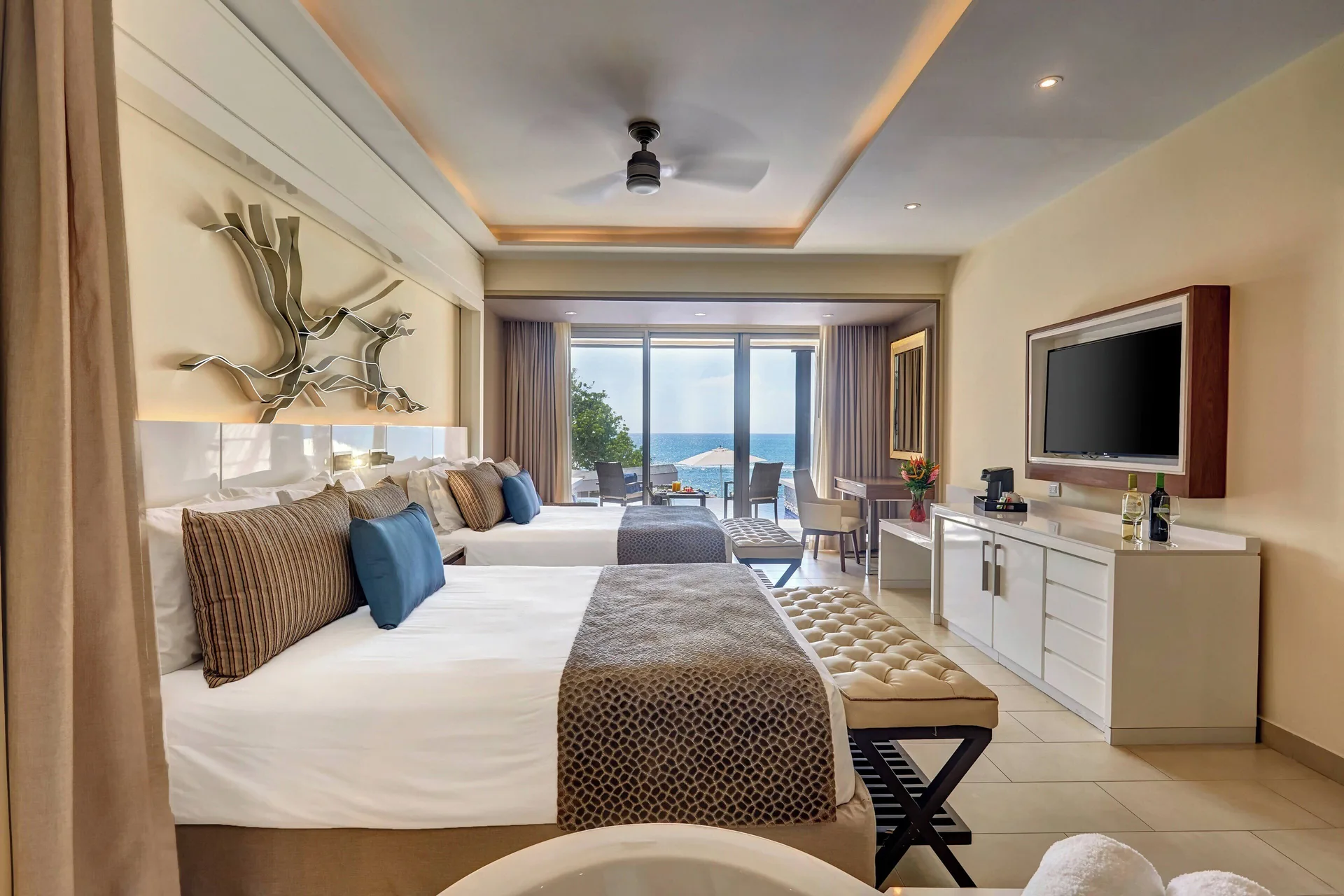 Sunset Swim Out Suite with two beds, TV, and ocean-facing doors at Grand Lido Negril Au-Naturel.