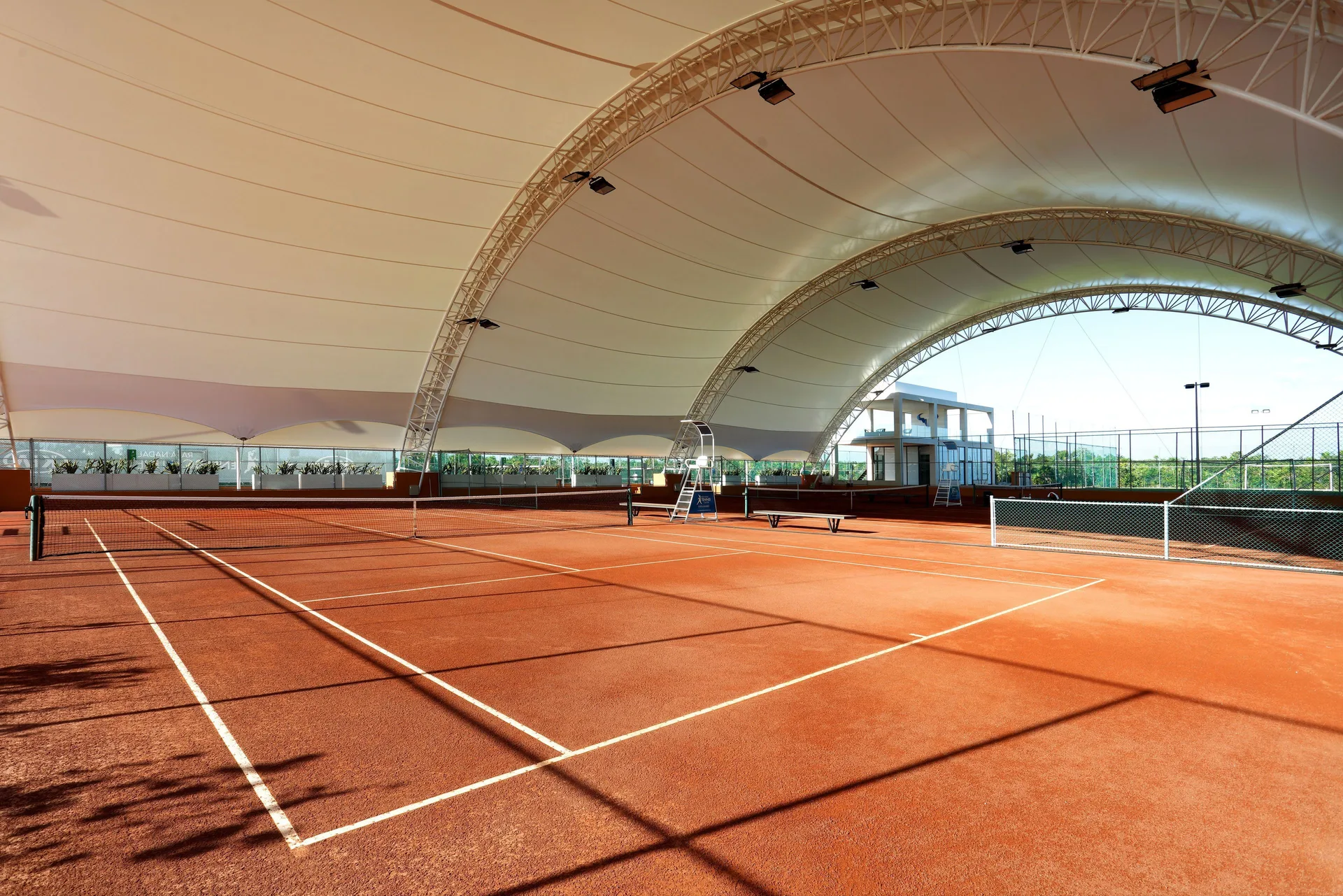 Covered tennis courts with clay-colored surfaces at Grand Palladium Select Costa Mujeres.