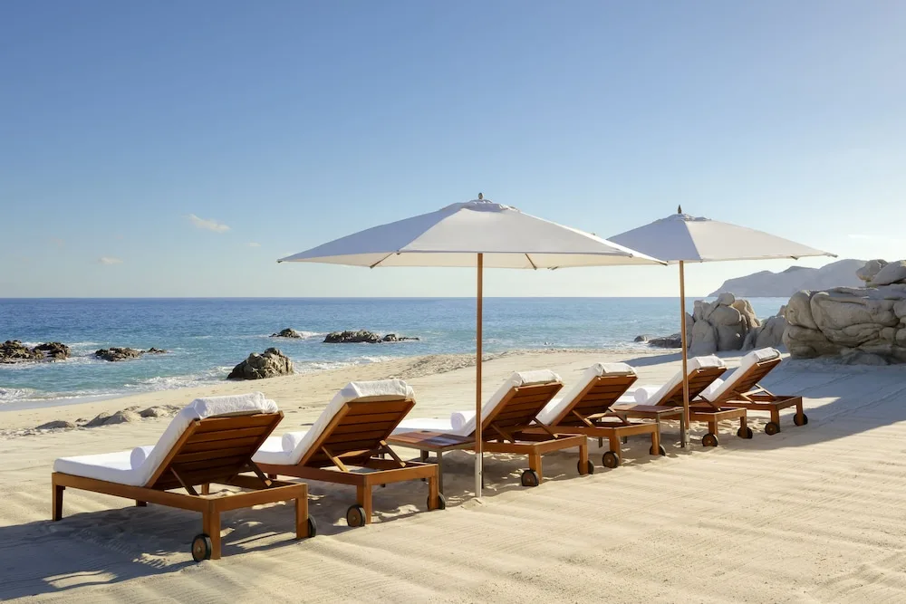 Beach loungers and white umbrellas face the ocean at Grand Velas Los Cabos.