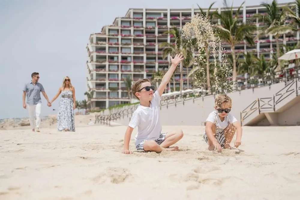 Children play in the sand while adults walk nearby at Grand Velas Los Cabos.