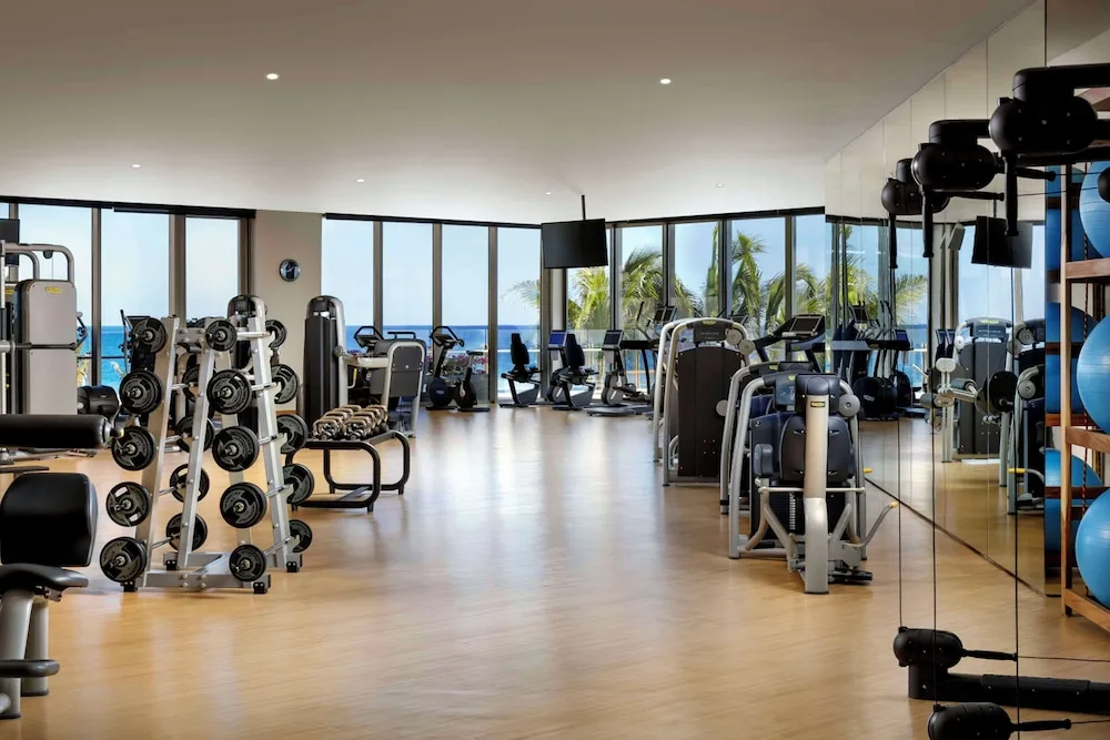 Fitness center with cardio machines, weights, mirrors, and ocean views at Grand Velas Los Cabos.