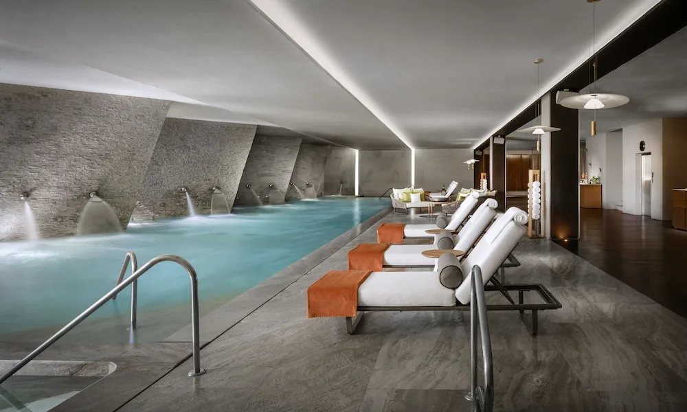 Indoor spa pool with white loungers and stone walls at Grand Velas Los Cabos.
