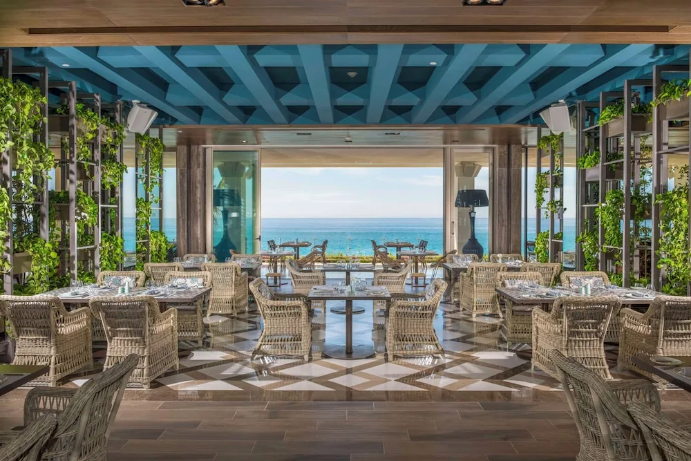 Bright dining room with wicker chairs and ocean view at Grand Velas Los Cabos.