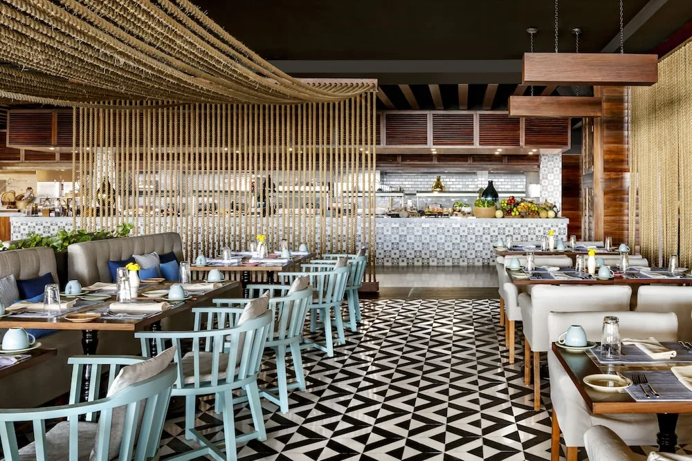 Restaurant dining room at Grand Velas Los Cabos with tiled floors, set tables, and buffet counters.