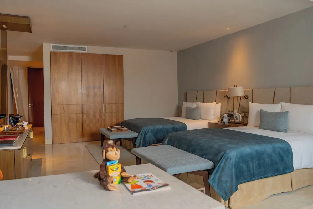 Family Duplex bedroom with two beds, wardrobe, and kids' items at Grand Velas Los Cabos.