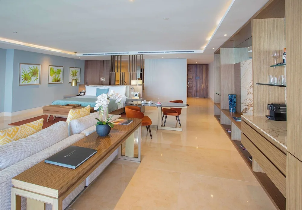 Grand Class Corner Suite with king bed, sofa, dining table, and minibar wall at Grand Velas Los Cabos.