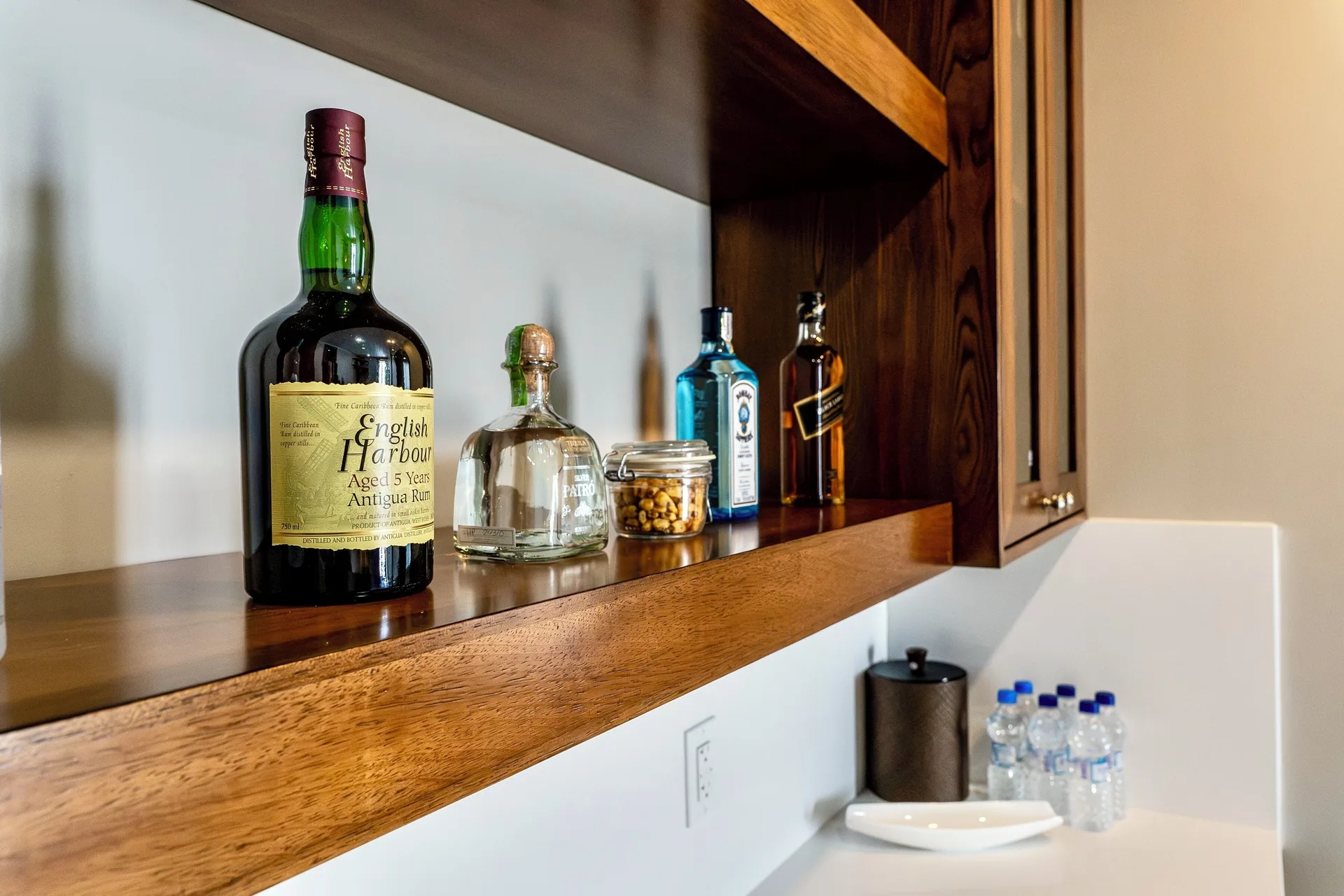 Signature Villa minibar shelf with spirits, snacks, and water at Hammock Cove Antigua.