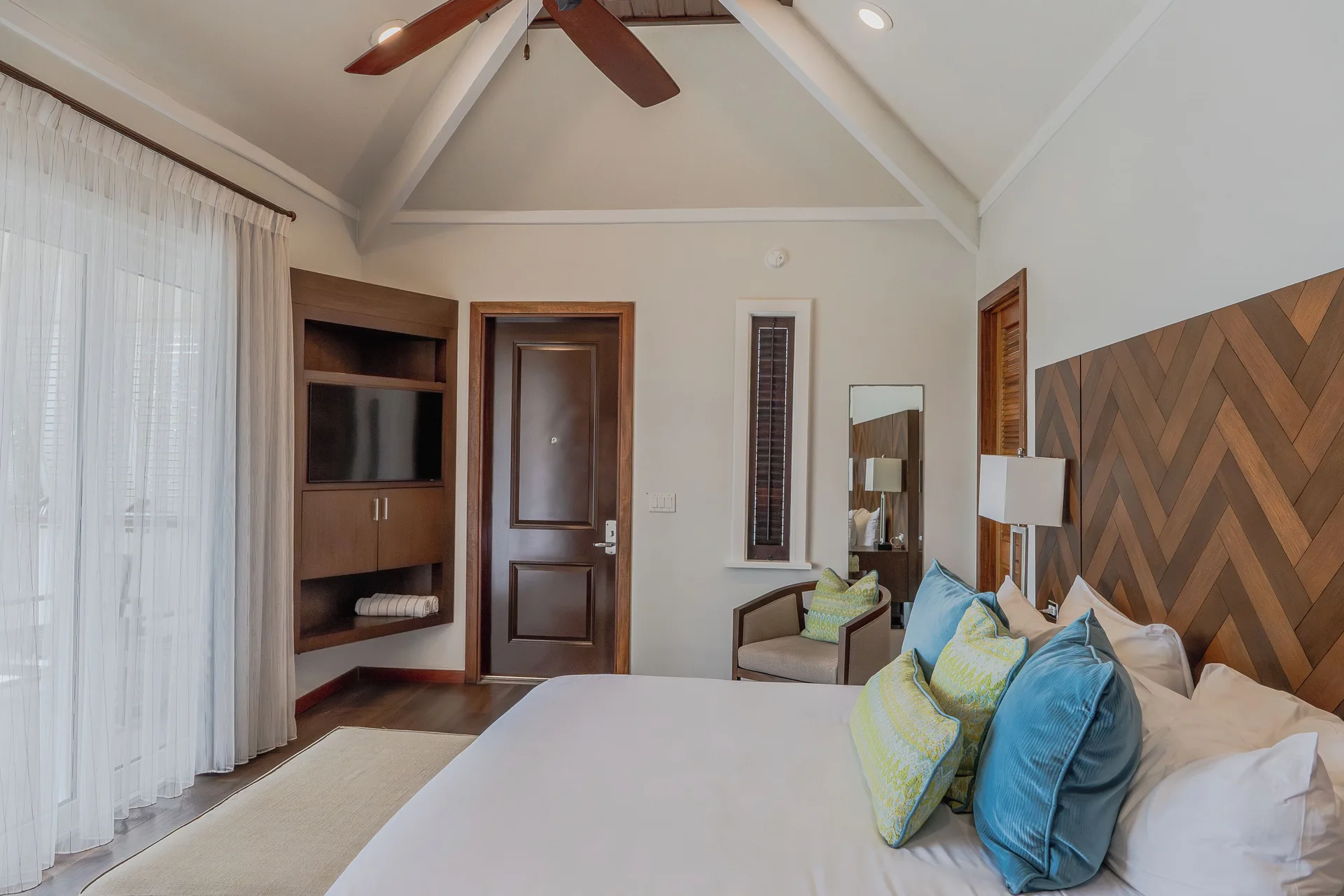 Waterview Villa king bedroom with TV cabinet, armchair and sheer curtains at Hammock Cove Antigua.