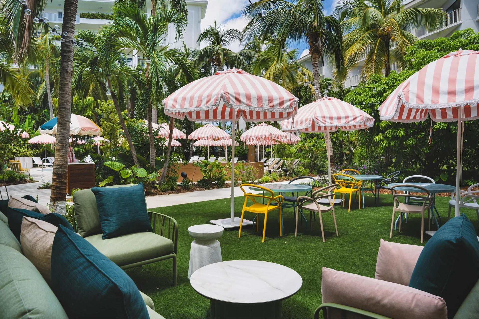 Daytime courtyard at Hampton by Hilton Grand Cayman Seven Mile Beach with striped umbrellas and lounge chairs.
