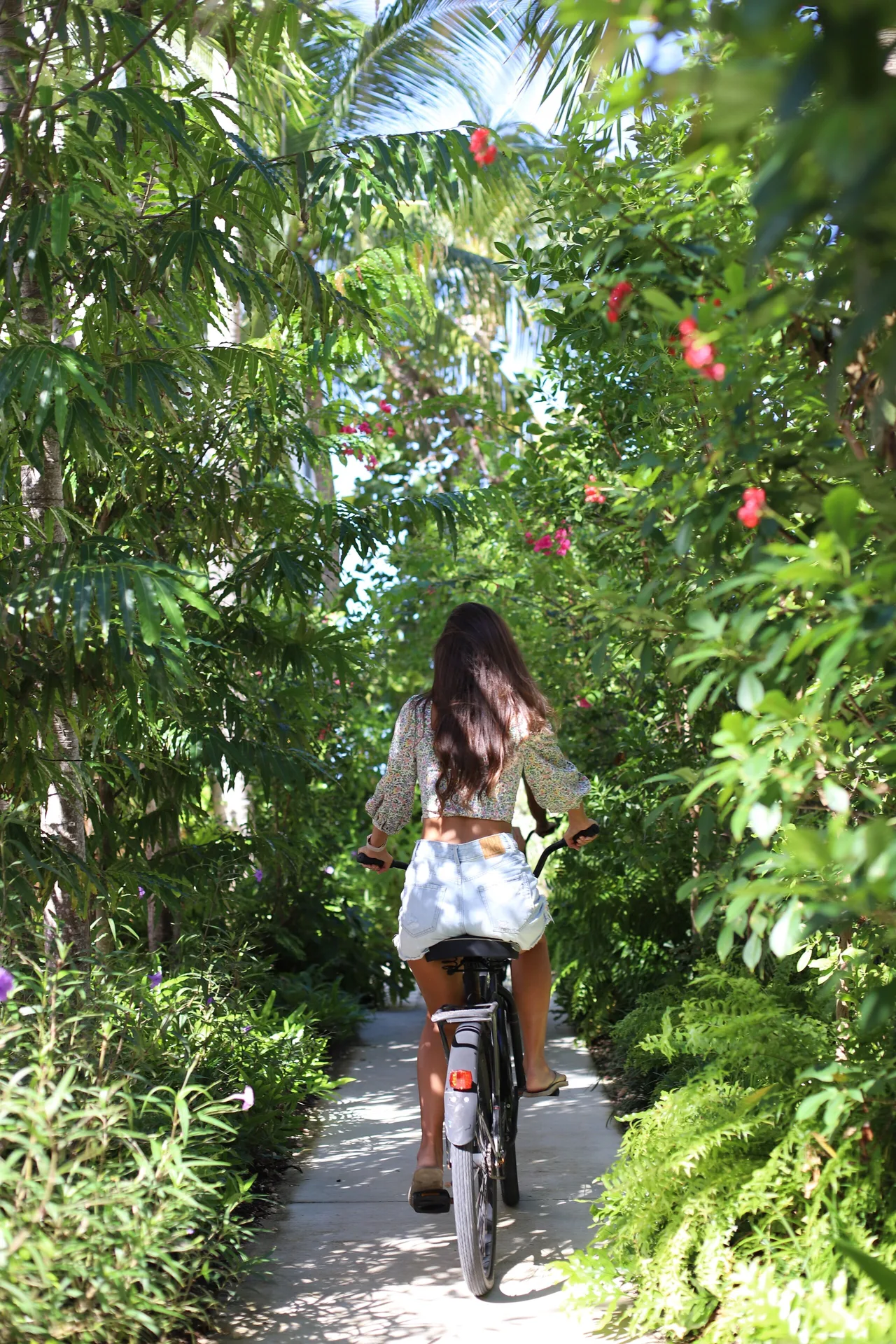 Guest bicycling along a garden path at Hampton by Hilton Grand Cayman Seven Mile Beach.