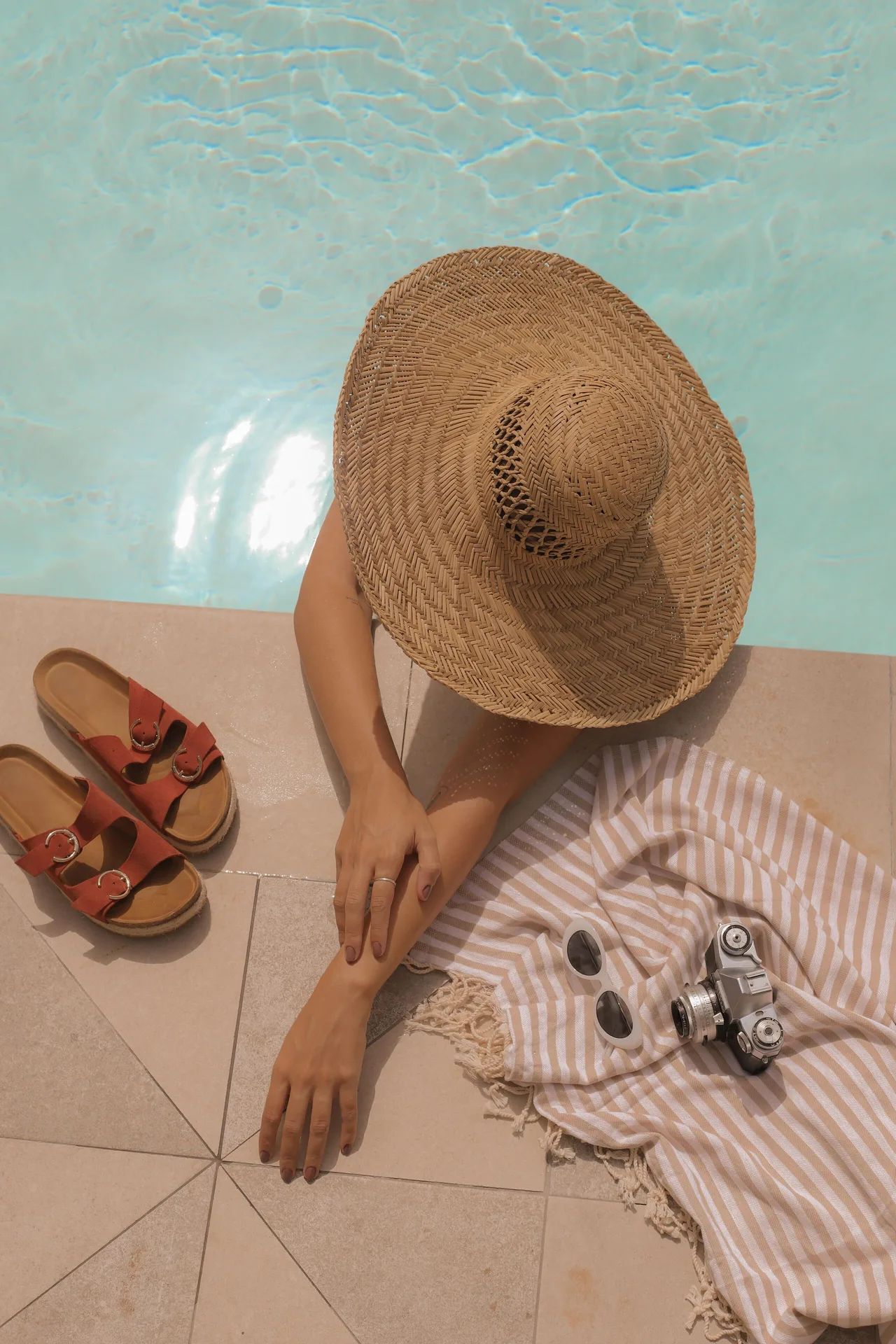 Poolside sun hat, sandals, towel, and camera at Hampton by Hilton Grand Cayman Seven Mile Beach.