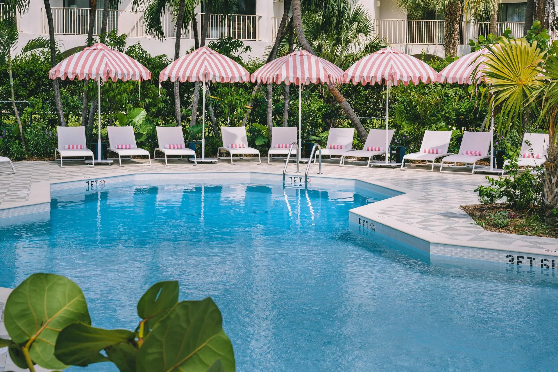 Resort pool with striped umbrellas at Hampton by Hilton Grand Cayman Seven Mile Beach.