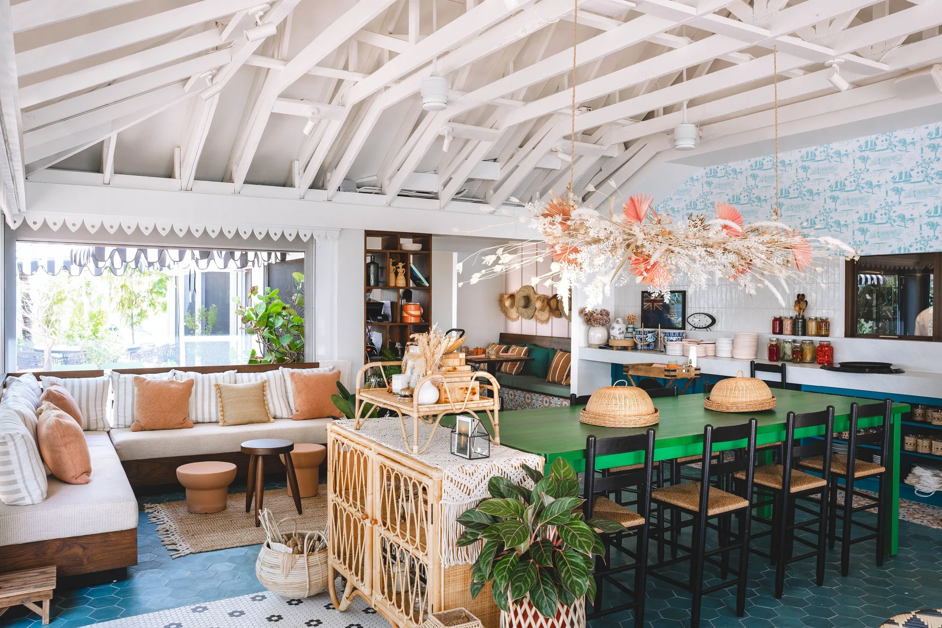 Bright lounge and dining area at Hampton by Hilton Grand Cayman Seven Mile Beach with wicker and green tables.