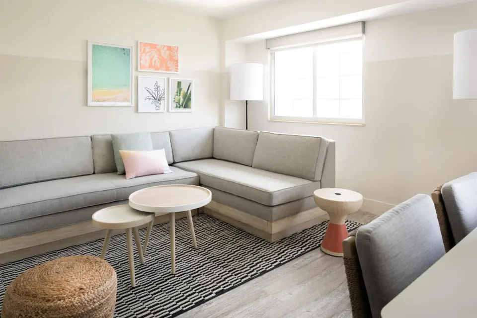 Executive Suite seating area at Hampton by Hilton Grand Cayman Seven Mile Beach with sectional sofa and tables.