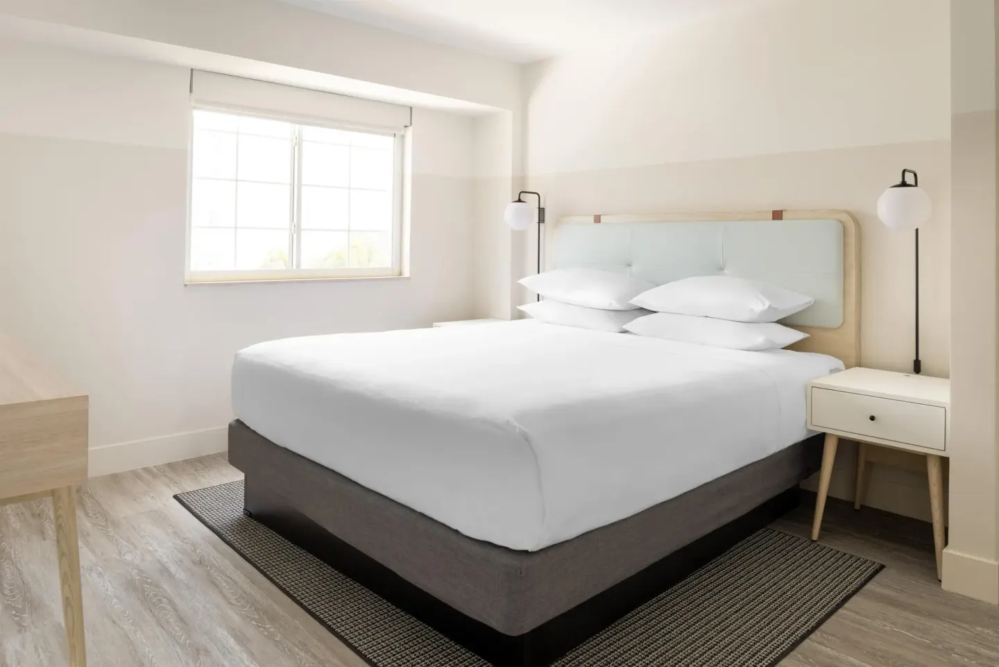 Standard Room partial ocean view king bed by a bright window at Hampton by Hilton Grand Cayman Seven Mile Beach.