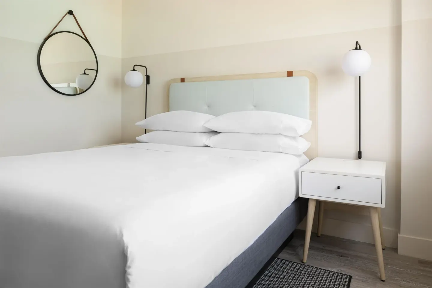 Standard room king bed with round wall mirror at Hampton by Hilton Grand Cayman Seven Mile Beach.