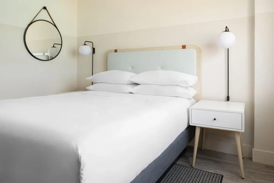 Standard room king bed with round wall mirror at Hampton by Hilton Grand Cayman Seven Mile Beach.