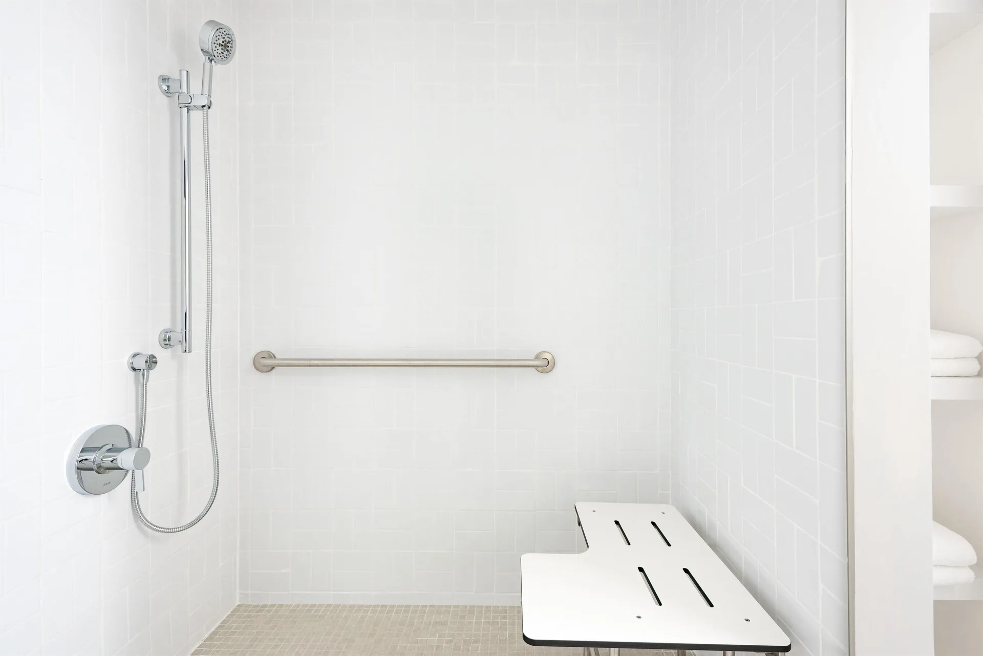 Accessible roll-in shower with bench and grab bar at Hampton by Hilton Grand Cayman Seven Mile Beach.