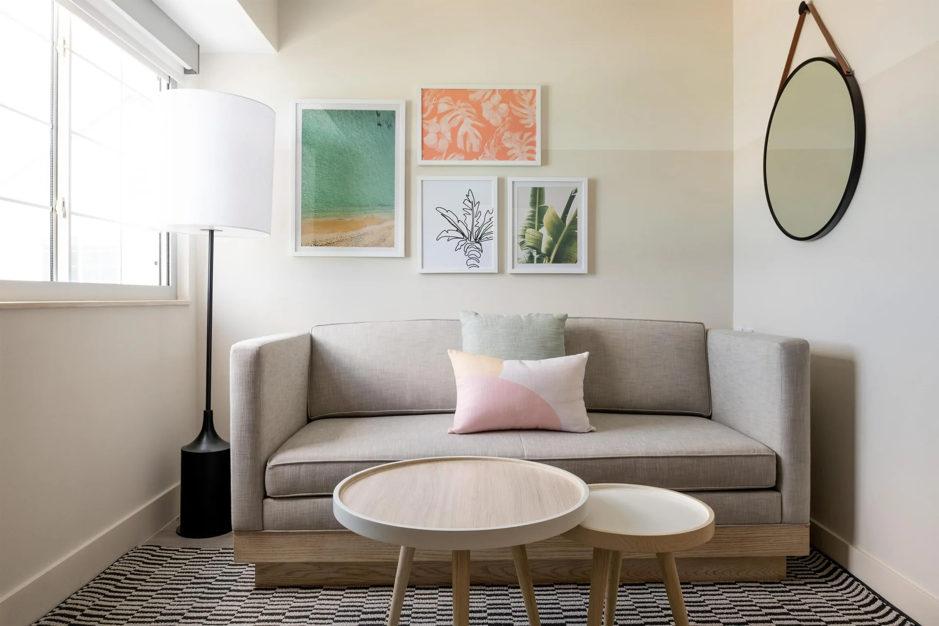 Sofa, nesting tables, window, and wall art in a studio at Hampton by Hilton Grand Cayman Seven Mile Beach.