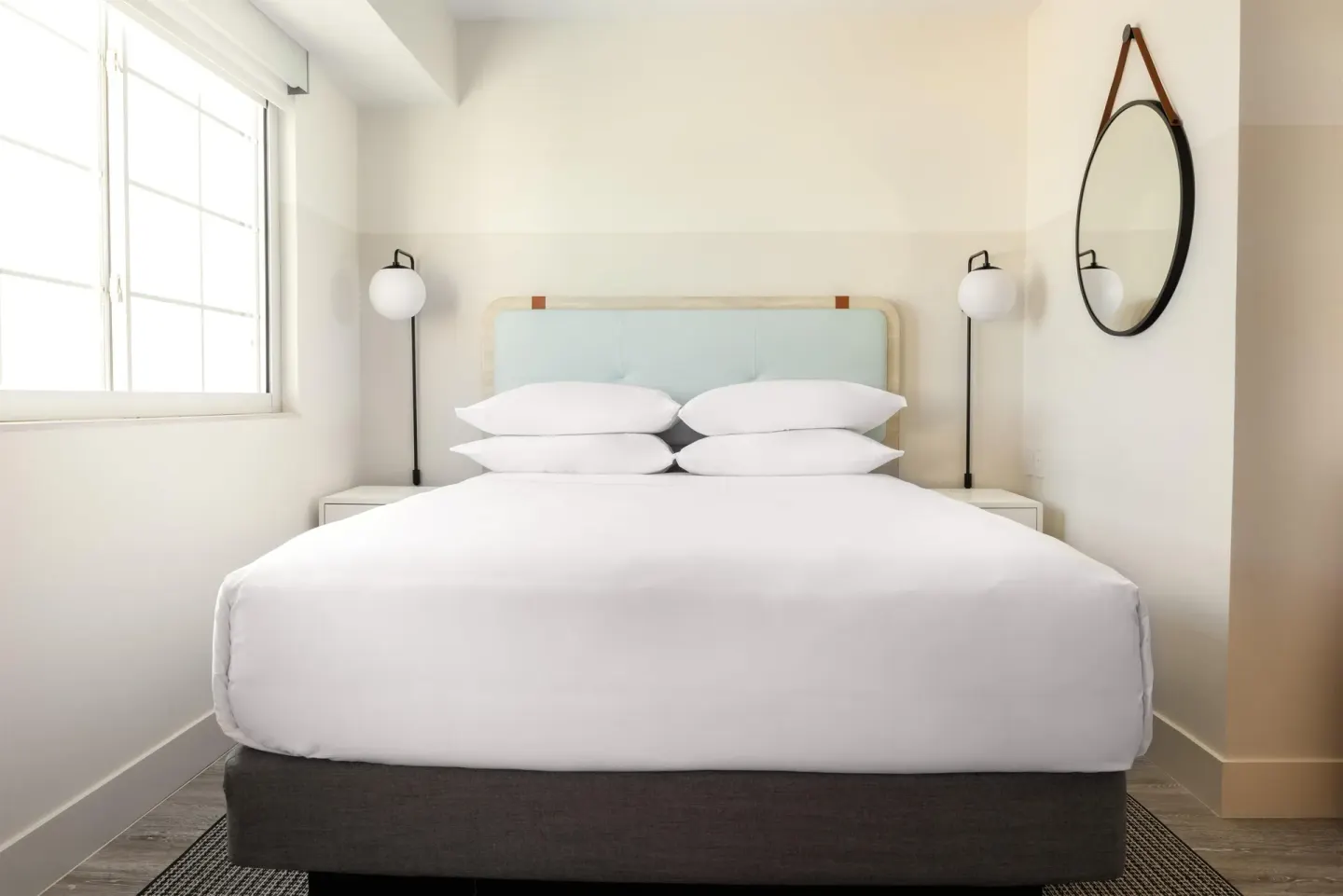 Studio king bed with round wall mirror at Hampton by Hilton Grand Cayman Seven Mile Beach.