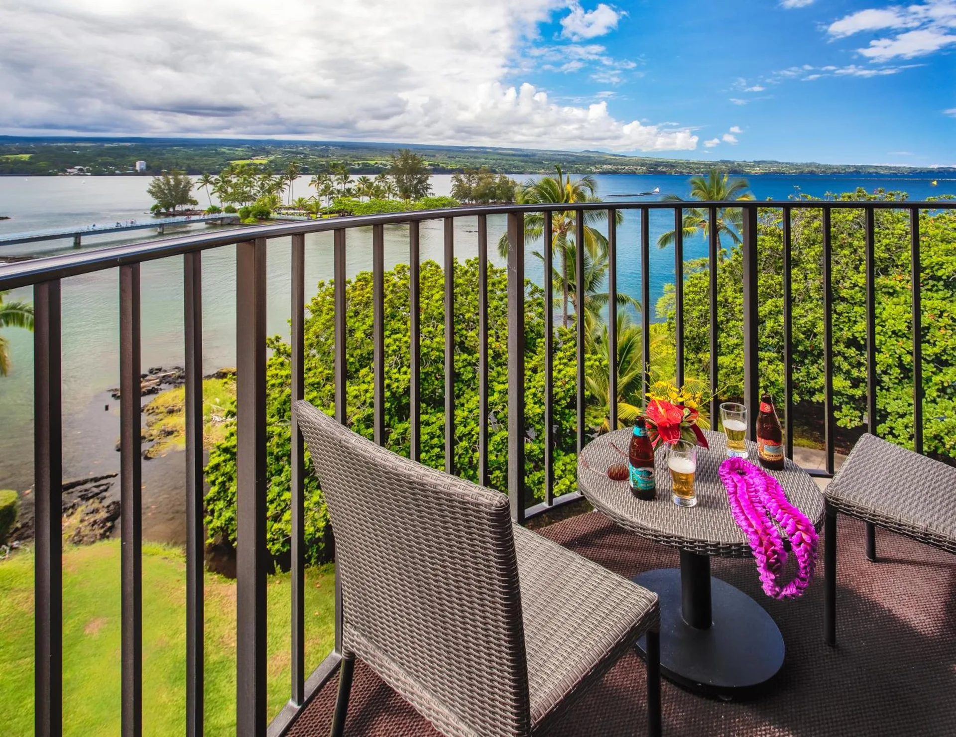 Oceanfront balcony with seating and bay view at Hilo Hawaiian Hotel.
