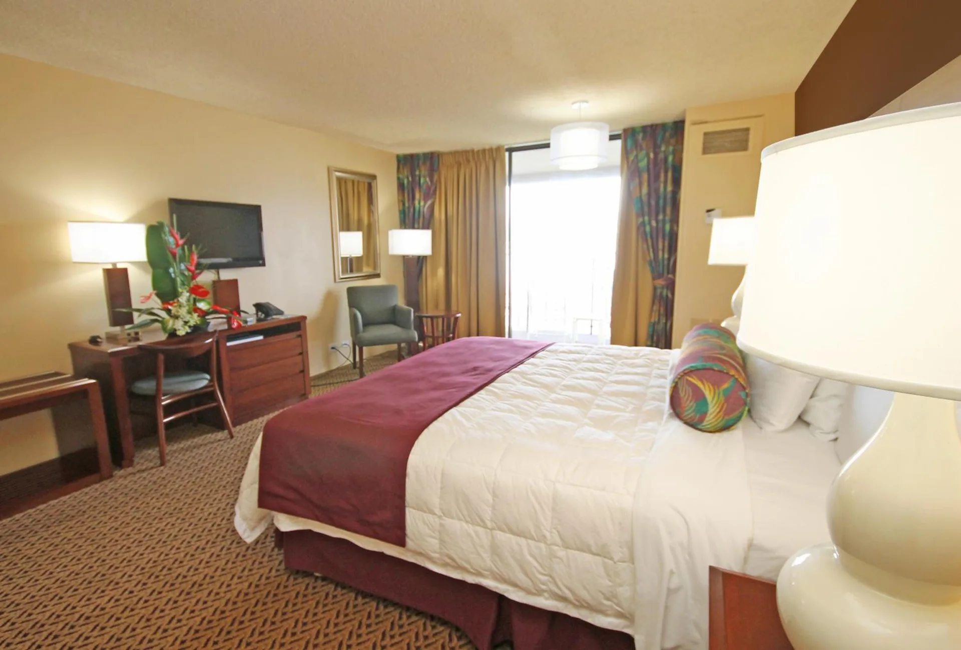 Oceanfront suite bedroom with king bed, desk, and TV at Hilo Hawaiian Hotel.