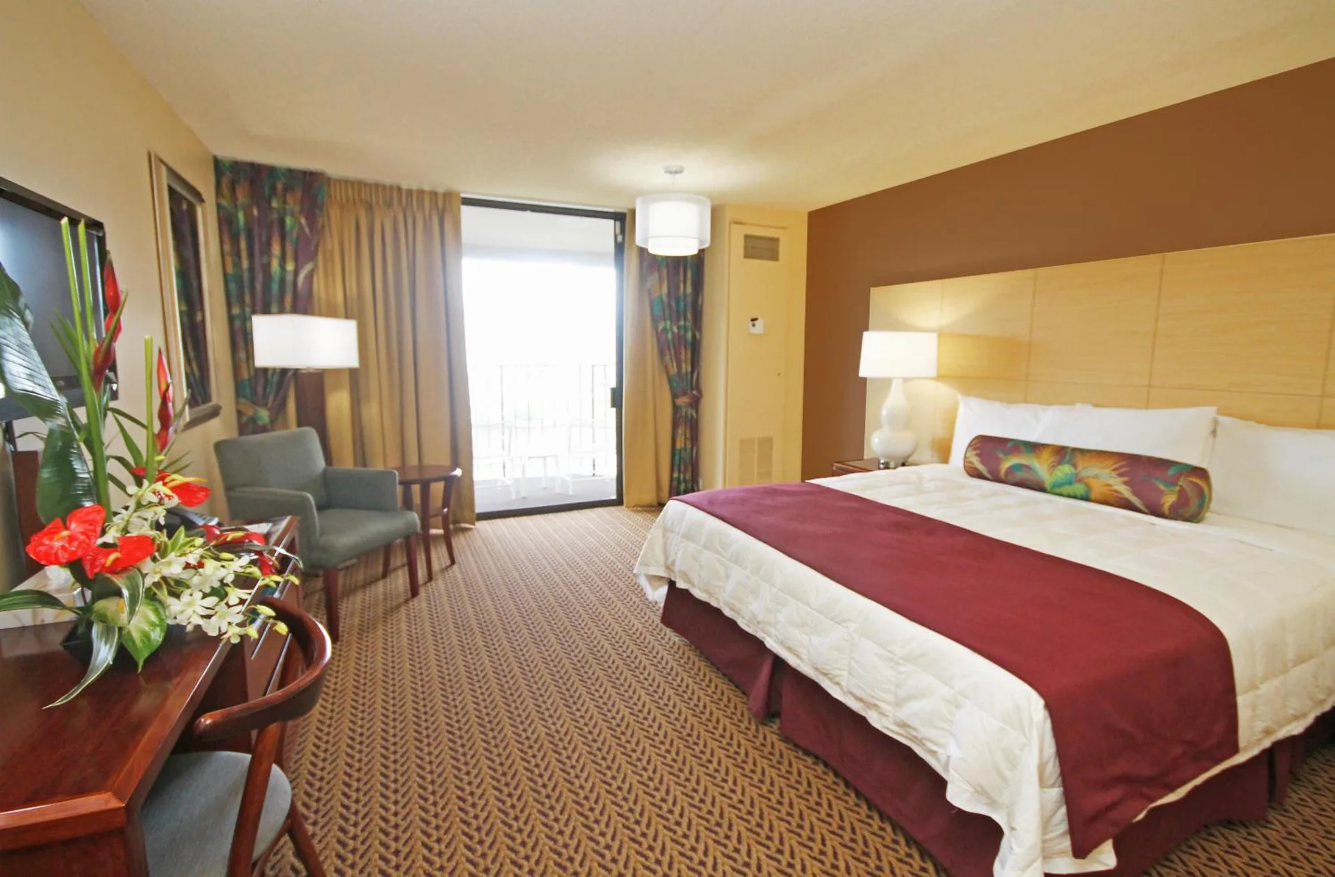 Oceanfront suite bedroom with king bed and seating at Hilo Hawaiian Hotel.