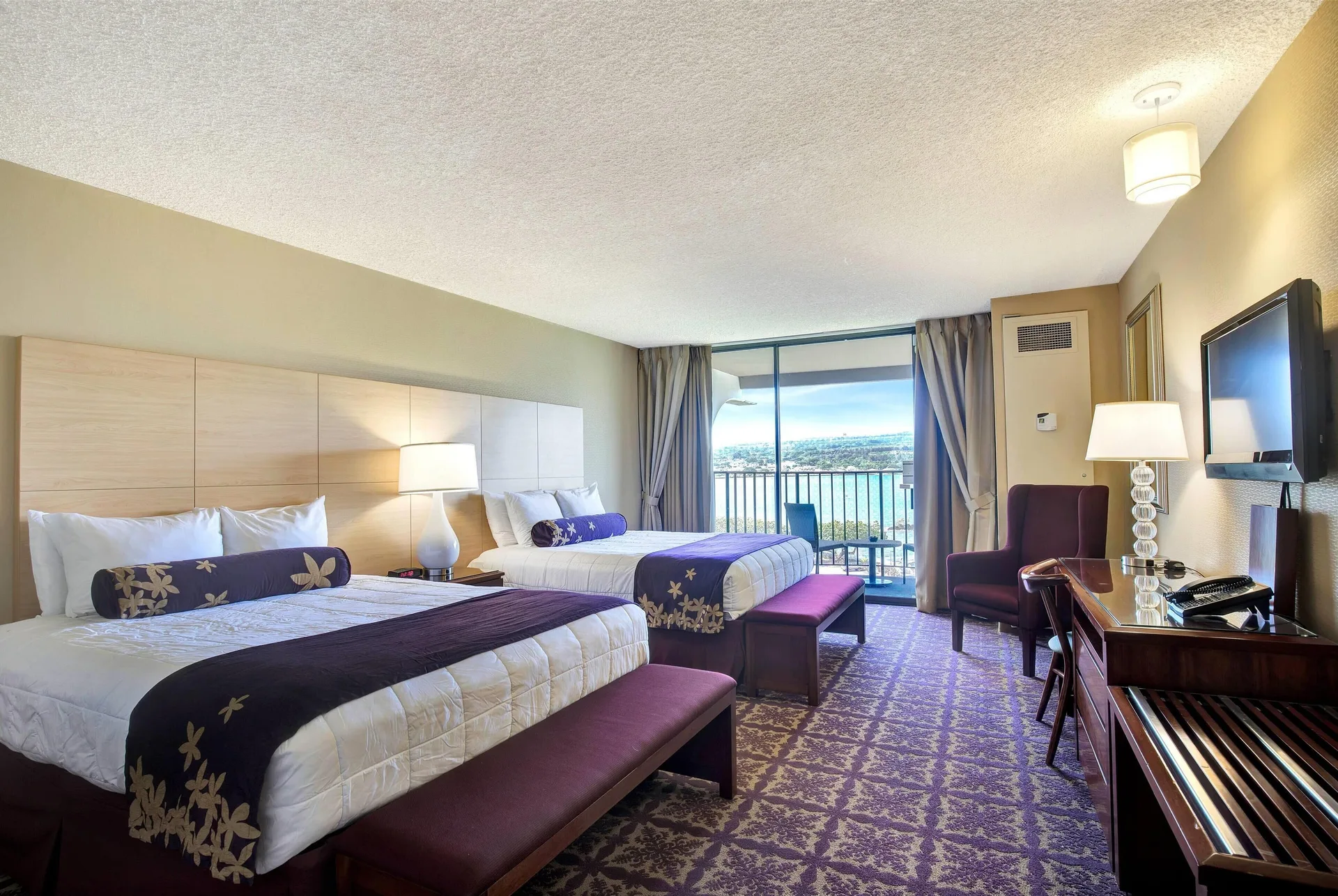 Oceanfront suite bedroom with two beds and balcony at Hilo Hawaiian Hotel.